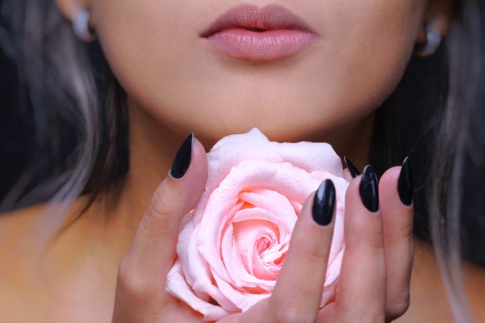 Femeie tanara care tine in mana un trandafir roz - portret 